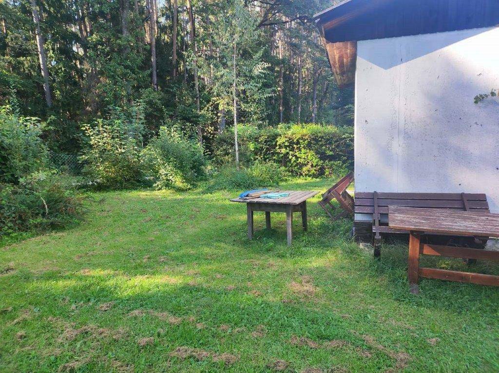 Sonniger Gartenbereich neben dem Gebäude mit rustikalen Holztischen und einer Bank für Mahlzeiten im Freien.