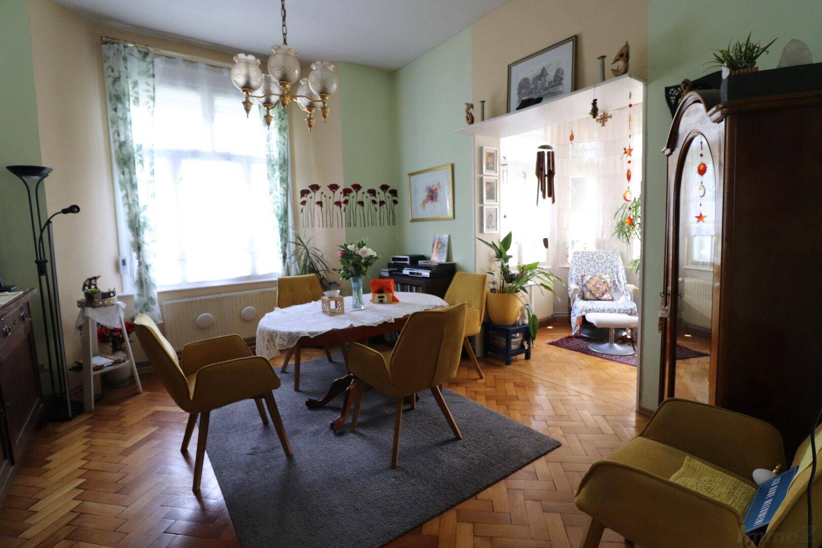 Gemütliches Esszimmer mit Parkettboden, runden Tisch und gelben Stühlen.
