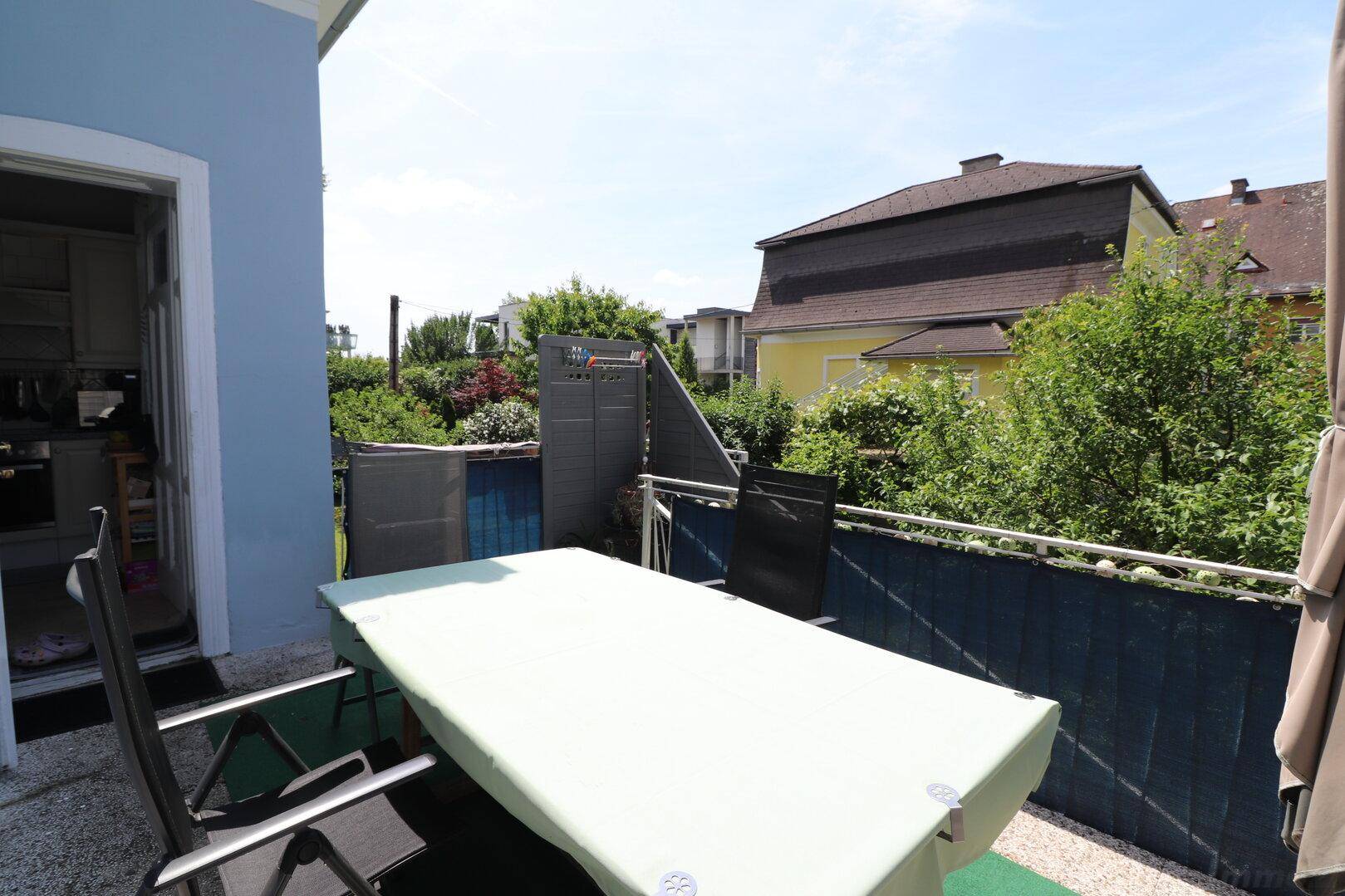 Gemütliche Terrasse mit Esstisch und Stühlen, umgeben von üppigem Grün.