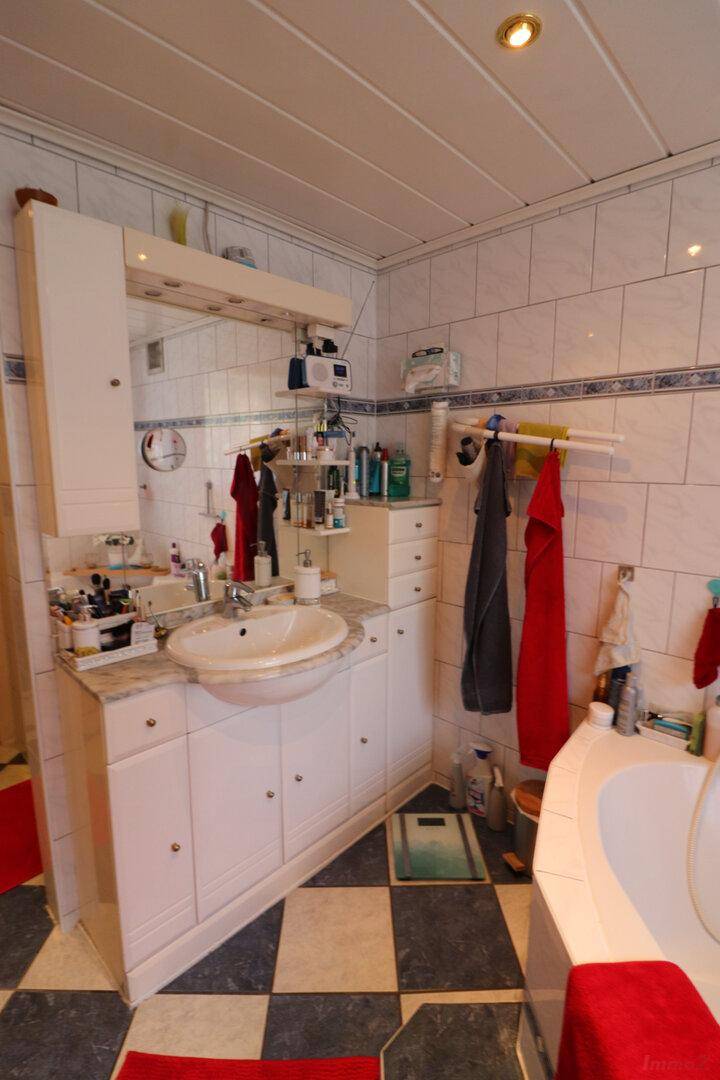 Badezimmer mit Waschtisch, Spiegel und Stauraum, passend zum Eck-Whirlpool.