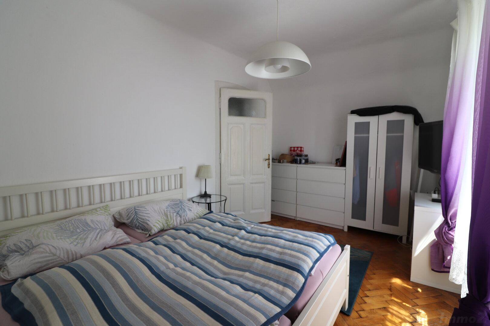 Helles Schlafzimmer mit Doppelbett, weißen Möbeln und klassischem Parkettboden.