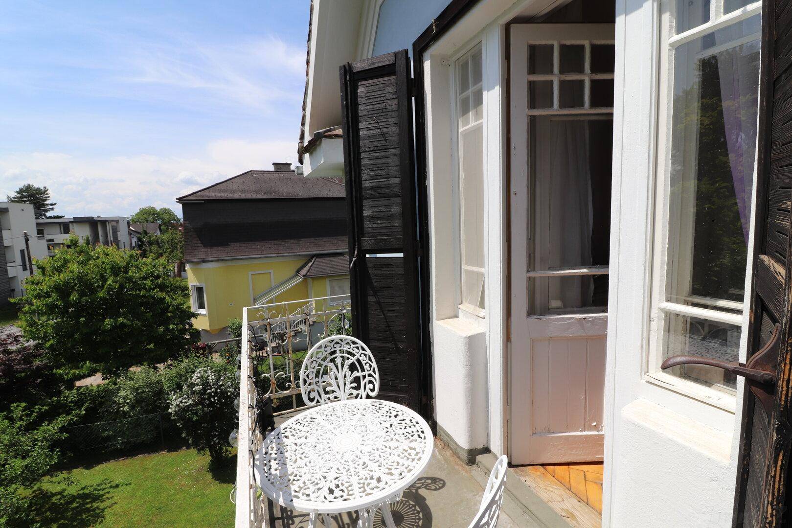 Balkon mit Zugangstür und schmiedeeisernen Möbeln, ideal für entspannte Stunden.