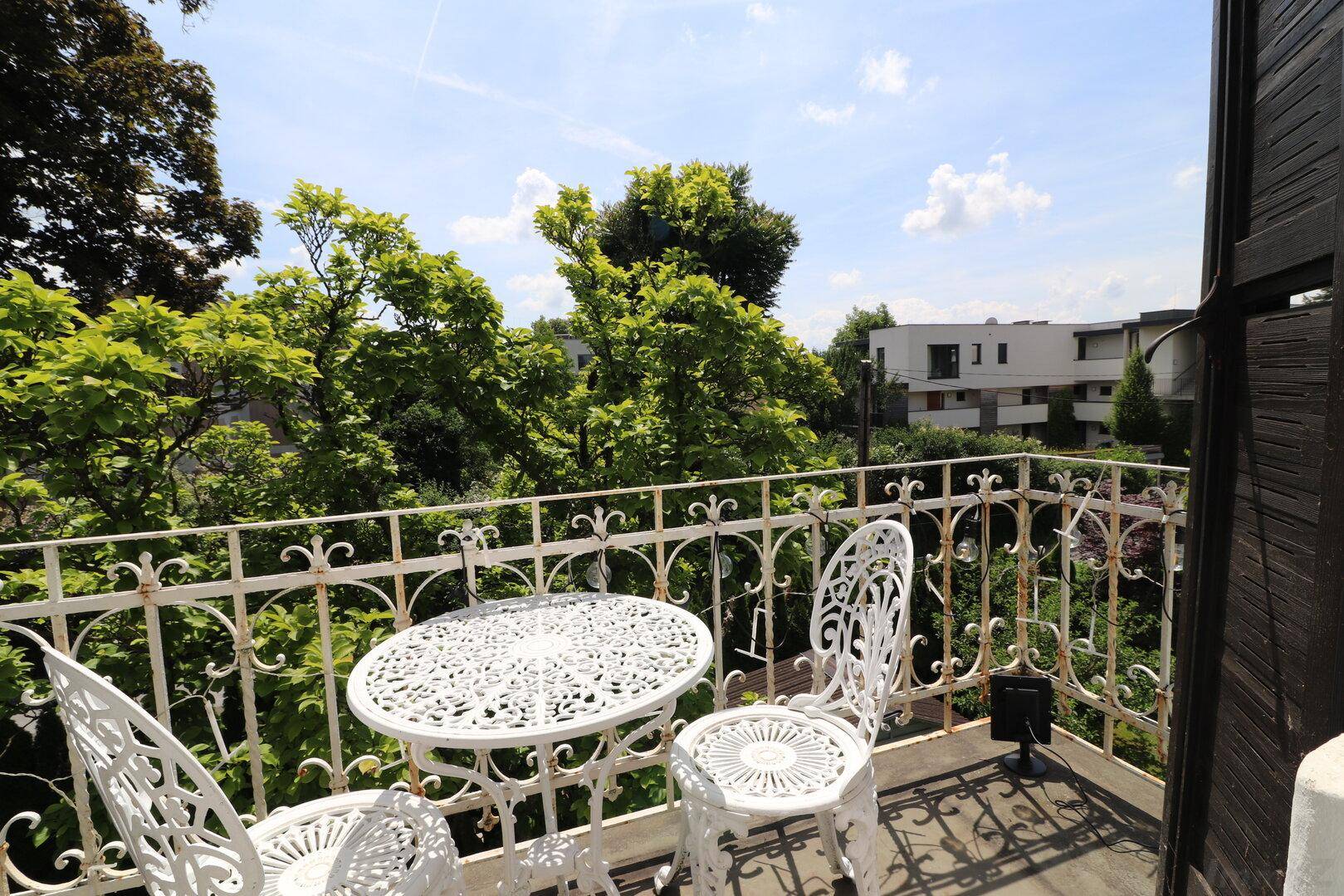 Romantischer Balkon mit schmiedeeisernen Möbeln und Blick ins Grüne.