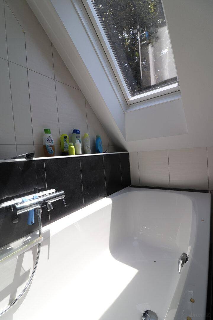 Badewanne unter einem Dachfenster im modernen Dachgeschossbad, hell und einladend.