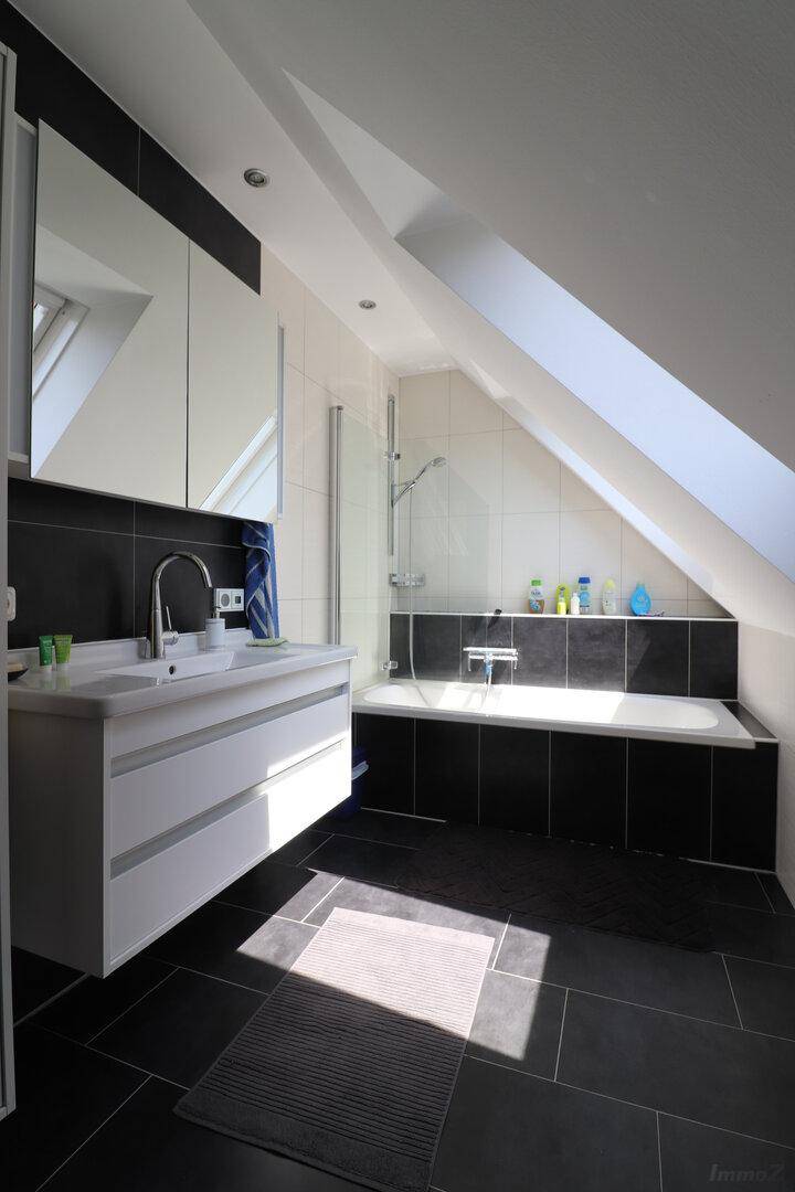 Modernes Dachgeschossbad mit Schrägdach, Dachfenster, Badewanne und stilvollem Waschtisch.