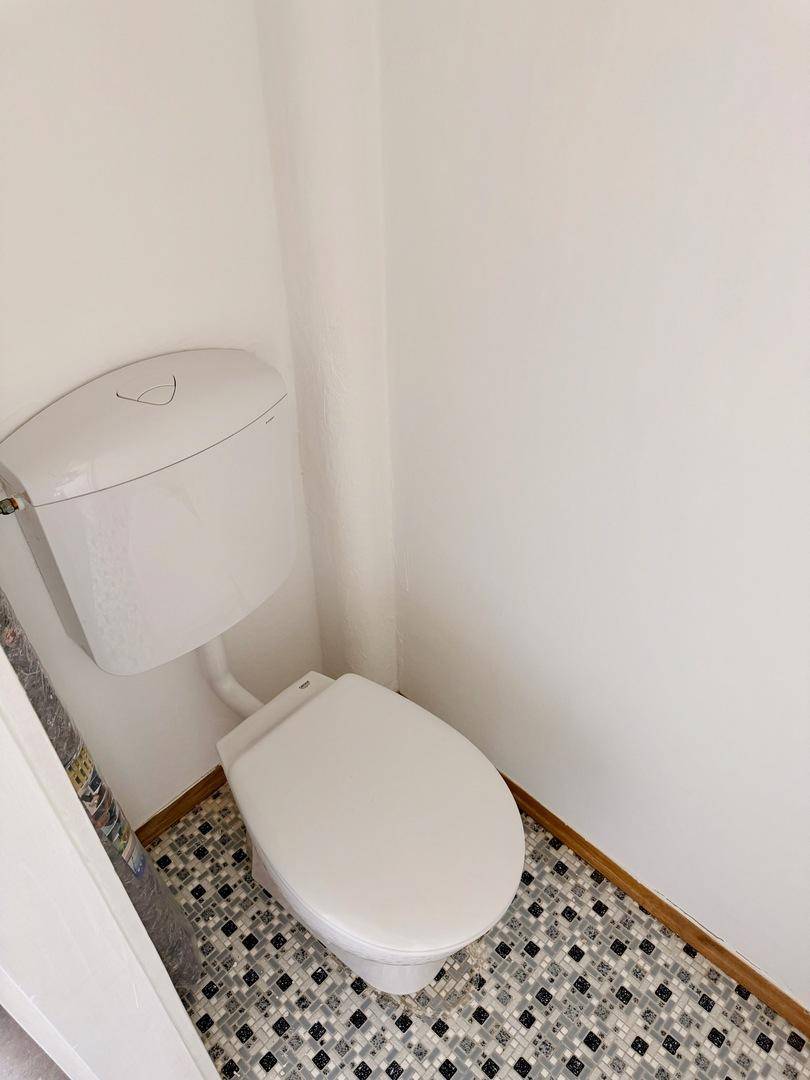 Separates WC mit Toilette und gemusterten Bodenfliesen in Schwarz-Weiß.