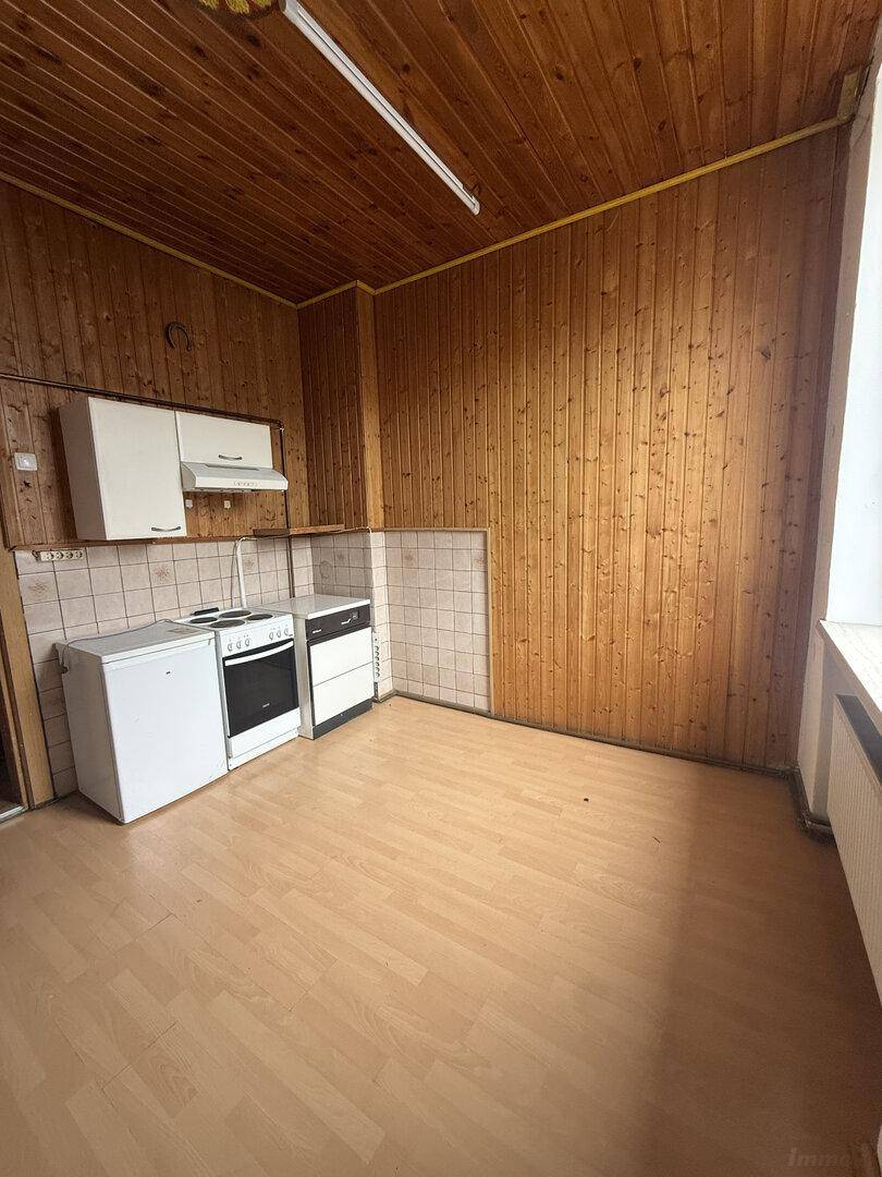 Einfache Küche mit Holzvertäfelung, Herd und Spüle, bietet Potenzial für eine Neugestaltung.