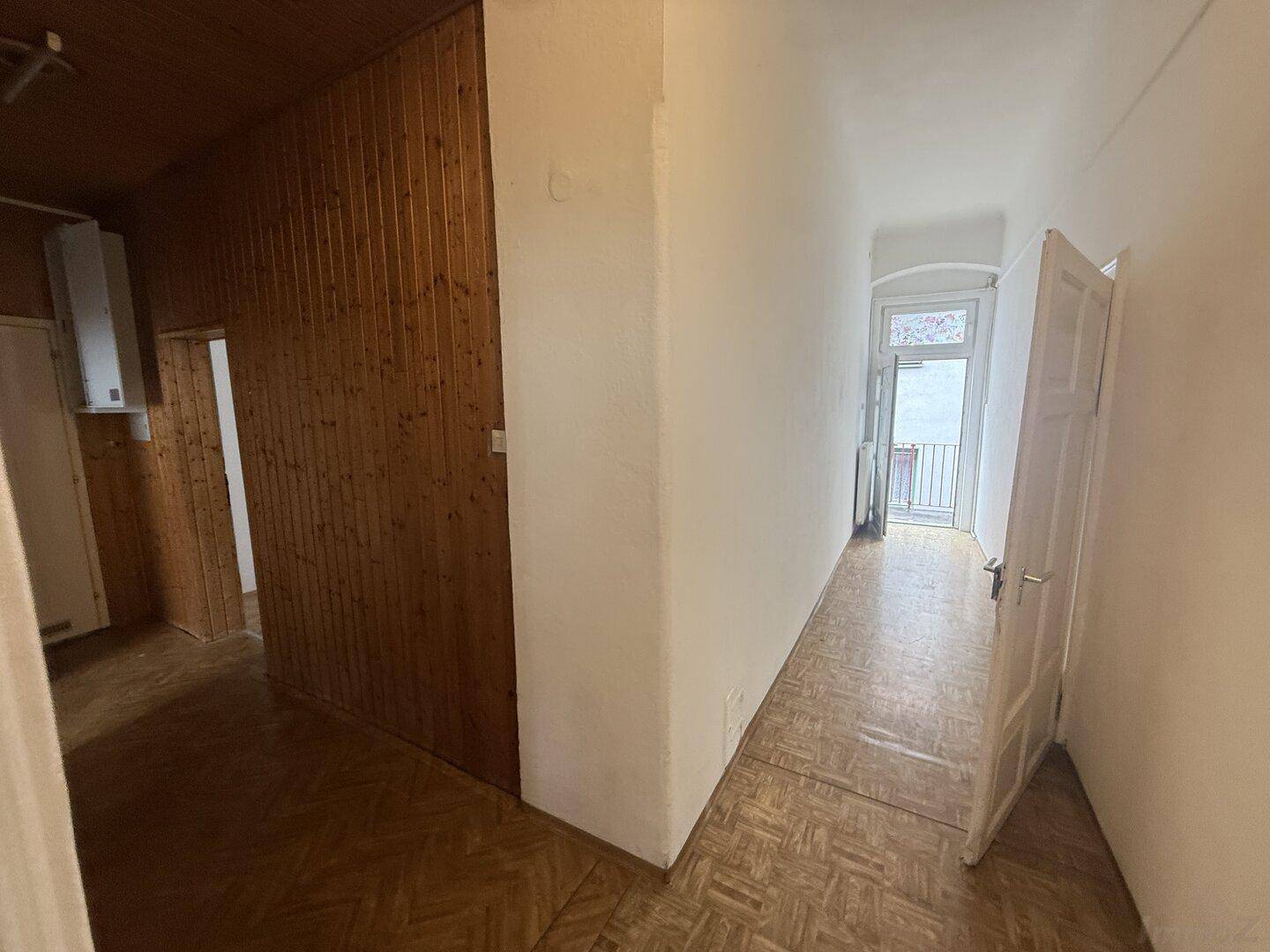 Flur mit Holzvertäfelung und Zugang zu einem französischen Balkon, der viel Licht spendet.
