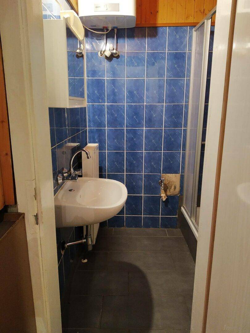 Kleines Badezimmer mit blauen Fliesen, Waschbecken und Duschkabine, funktional eingerichtet.