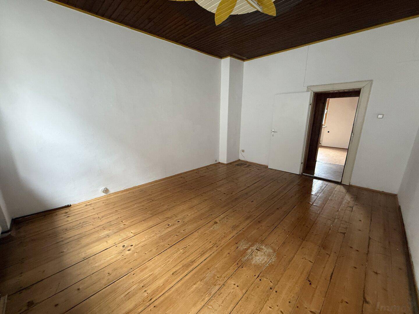 Helles Zimmer mit Holzdielenboden und Holzdecke, ideal für Wohn- oder Schlafbereich.