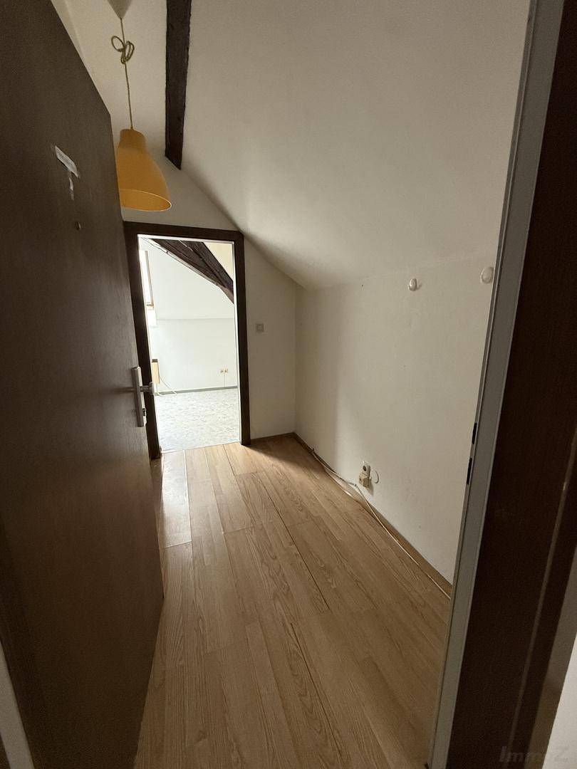 Heller Flur im Dachgeschoss mit Holzbalken und Laminatboden, der zu weiteren Räumen führt.