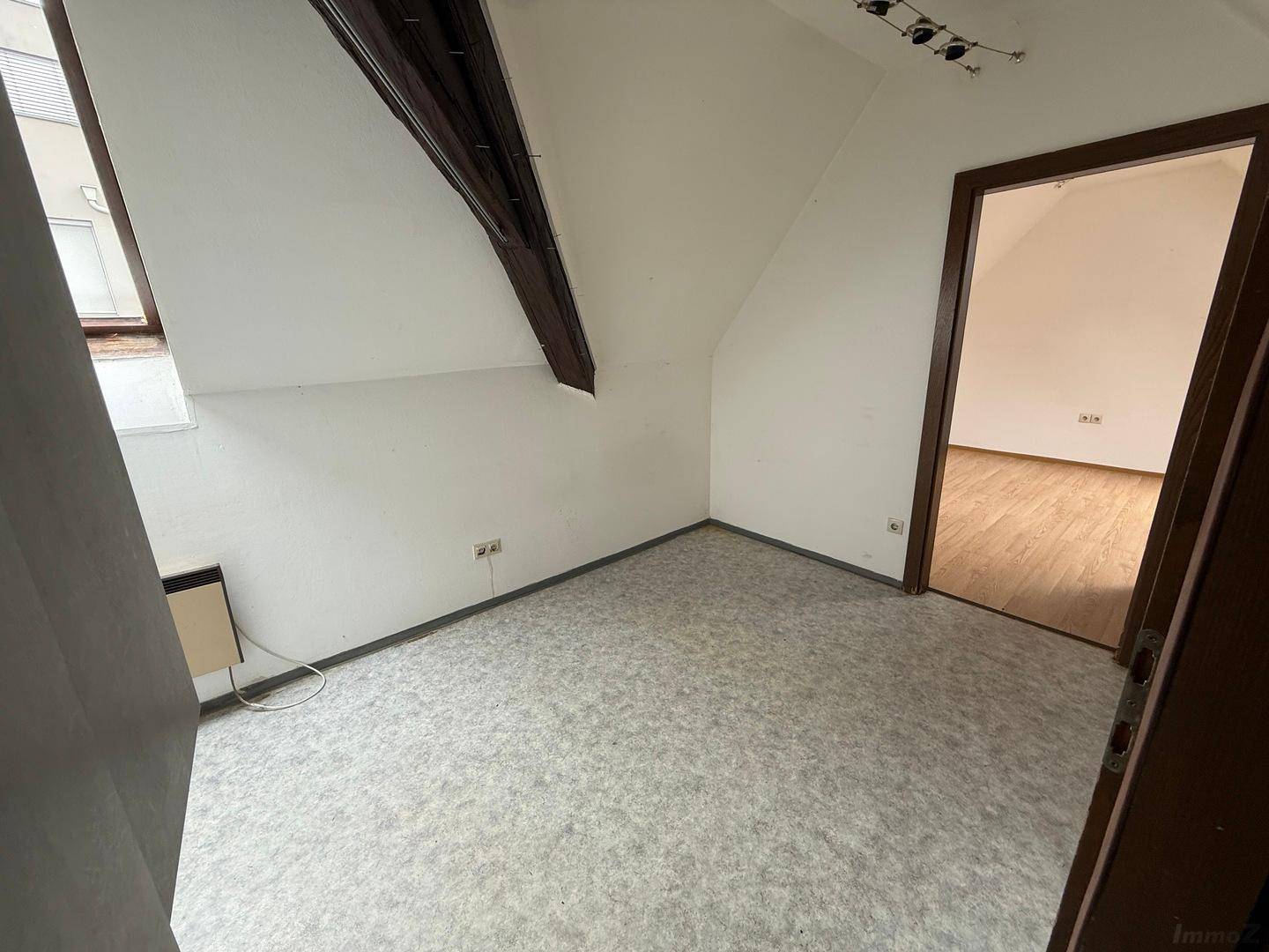 Schlafzimmer im Dachgeschoss mit Schrägdach, Teppichboden und einem Dachfenster für natürliches Licht.
