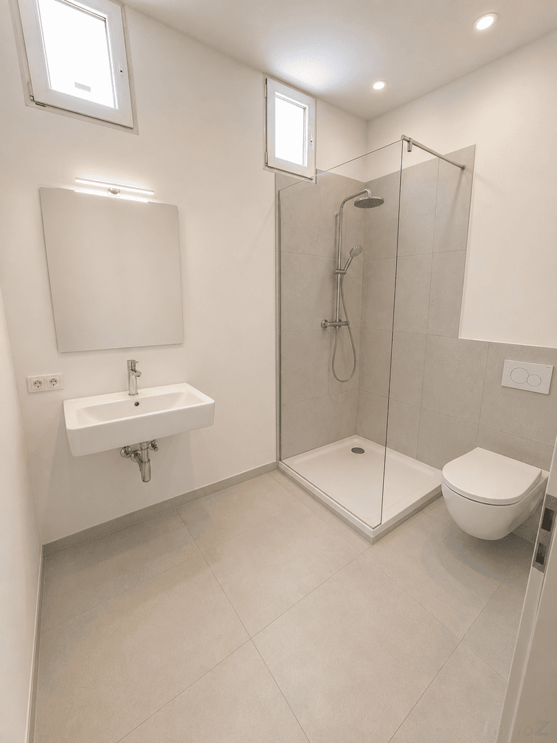 Modernes Badezimmer mit ebenerdiger Dusche, wandhängendem WC und kleinem Fenster.