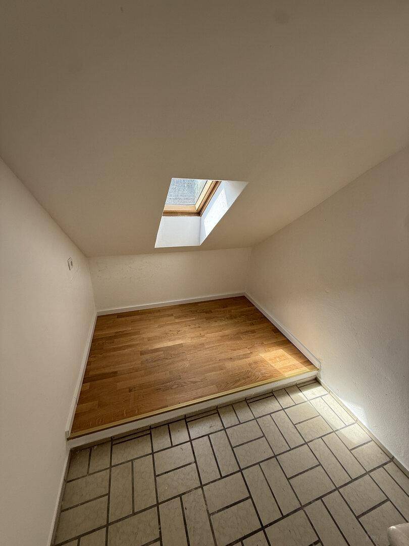 Kleiner Raum mit gemischtem Bodenbelag und einem Dachfenster für natürliches Licht.