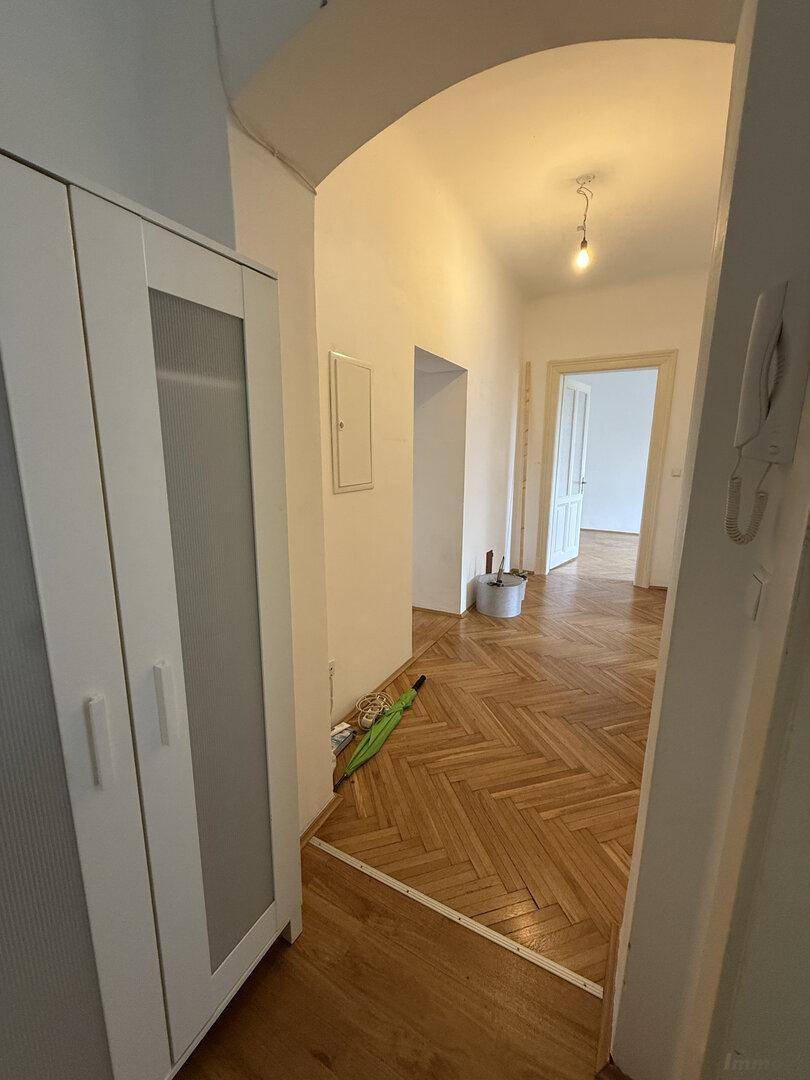 Geräumiger Flur mit Fischgrätparkett, einem eleganten Bogen und einem praktischen Kleiderschrank.