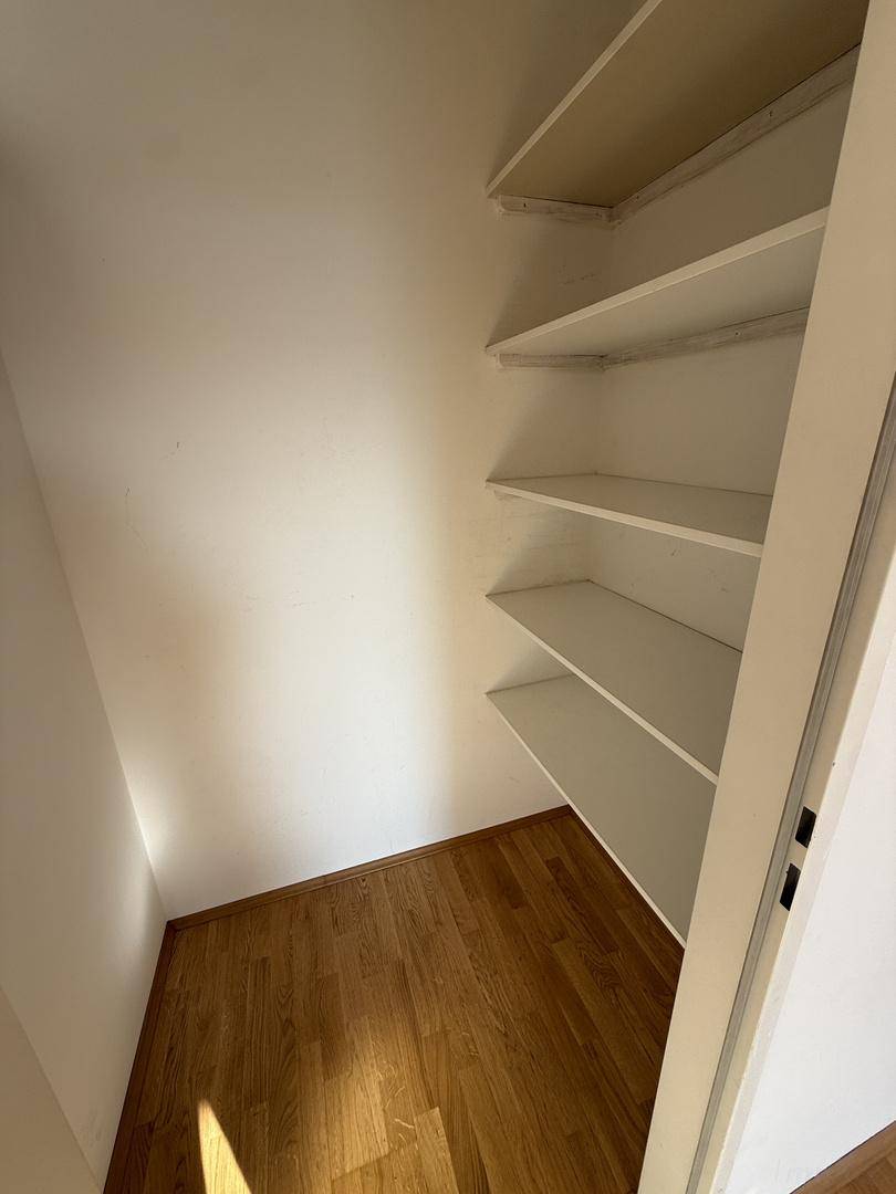 Praktischer Abstellraum mit mehreren Regalböden und Holzboden für zusätzlichen Stauraum.