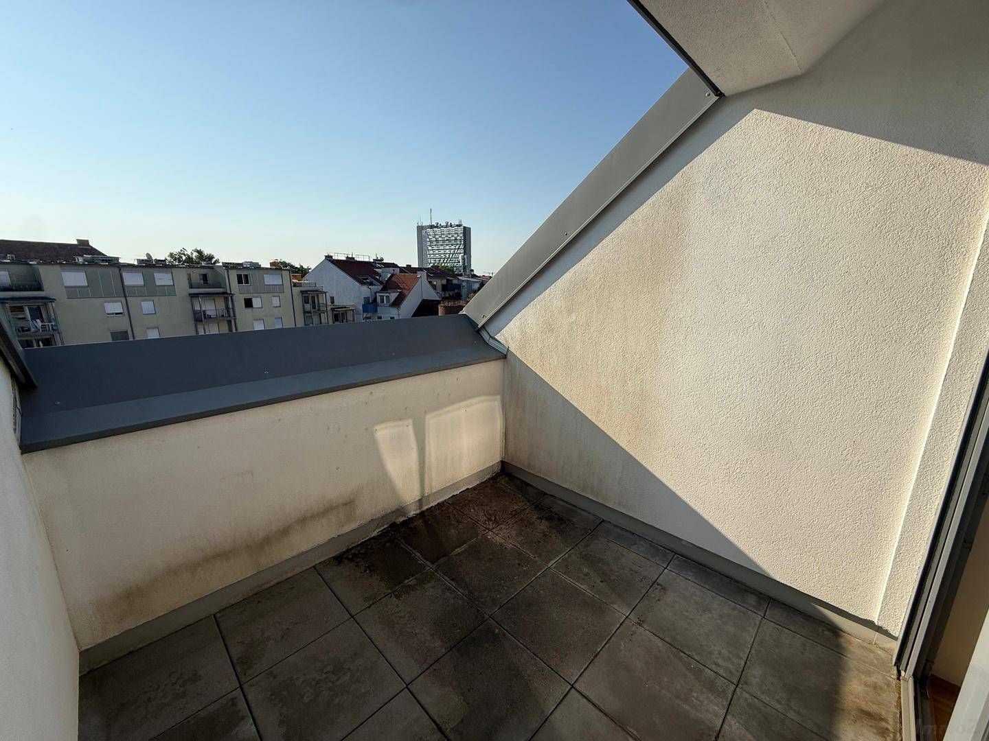 Geräumige Terrasse mit Fliesenboden und einem weiten Blick über die städtische Umgebung.
