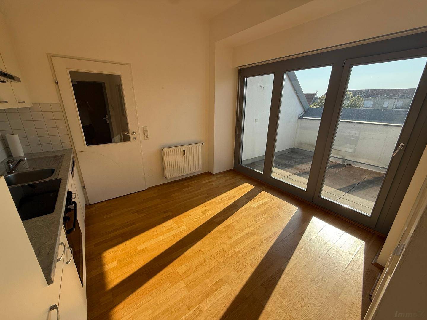 Helle Küche mit Holzboden und direktem Zugang zur Terrasse durch große Glasschiebetüren.