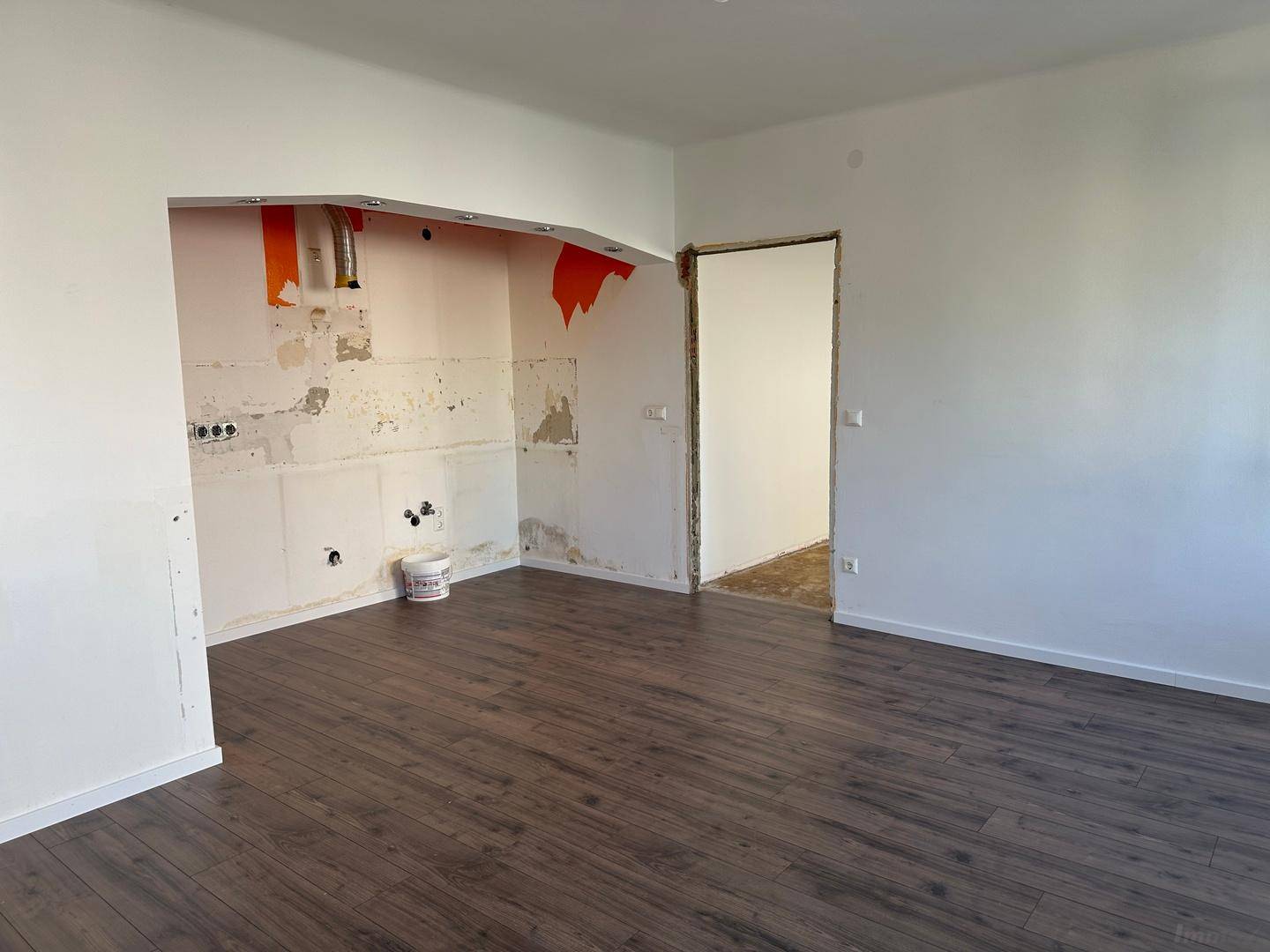 Detailansicht der vorbereiteten Küchennische mit Anschlüssen und neuem Laminatboden.