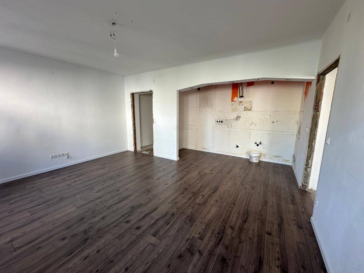 Raum mit neuem Laminatboden und vorbereiteter Nische für eine moderne Einbauküche.