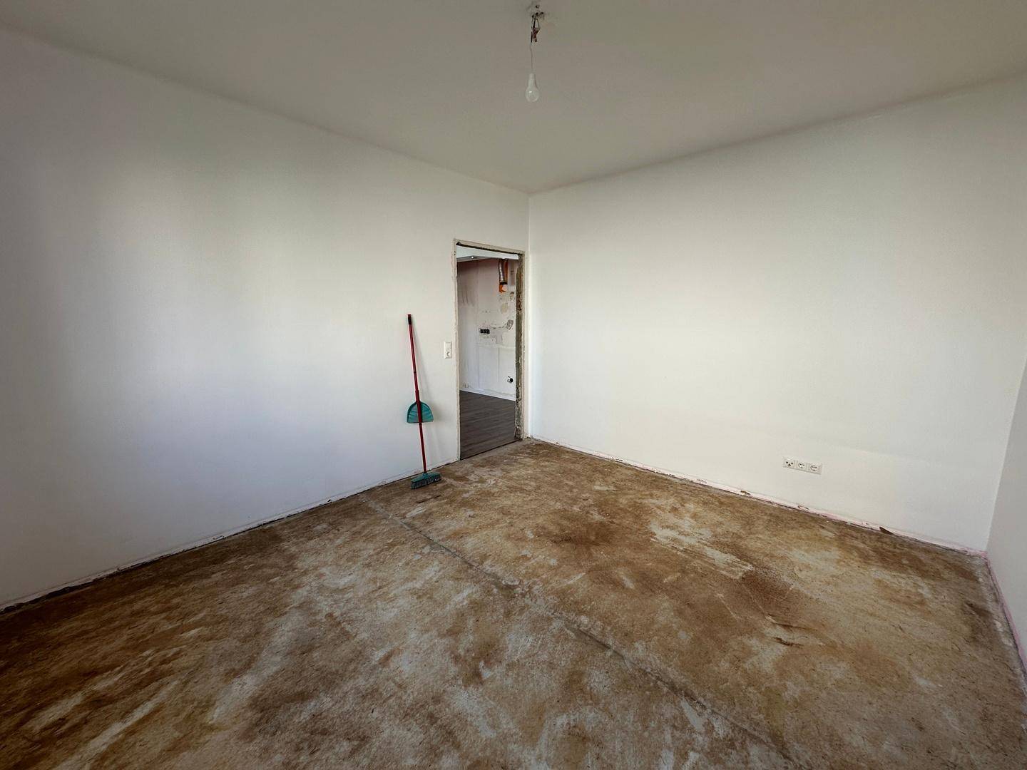 Unmöbliertes Zimmer mit vorbereitetem Bodenbelag und weißen Wänden, bereit zur Renovierung.