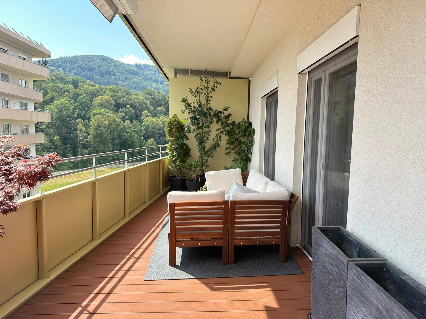 Breiter Balkon mit Sitzgelegenheiten, Pflanzen und Panoramablick auf die umliegende Natur.