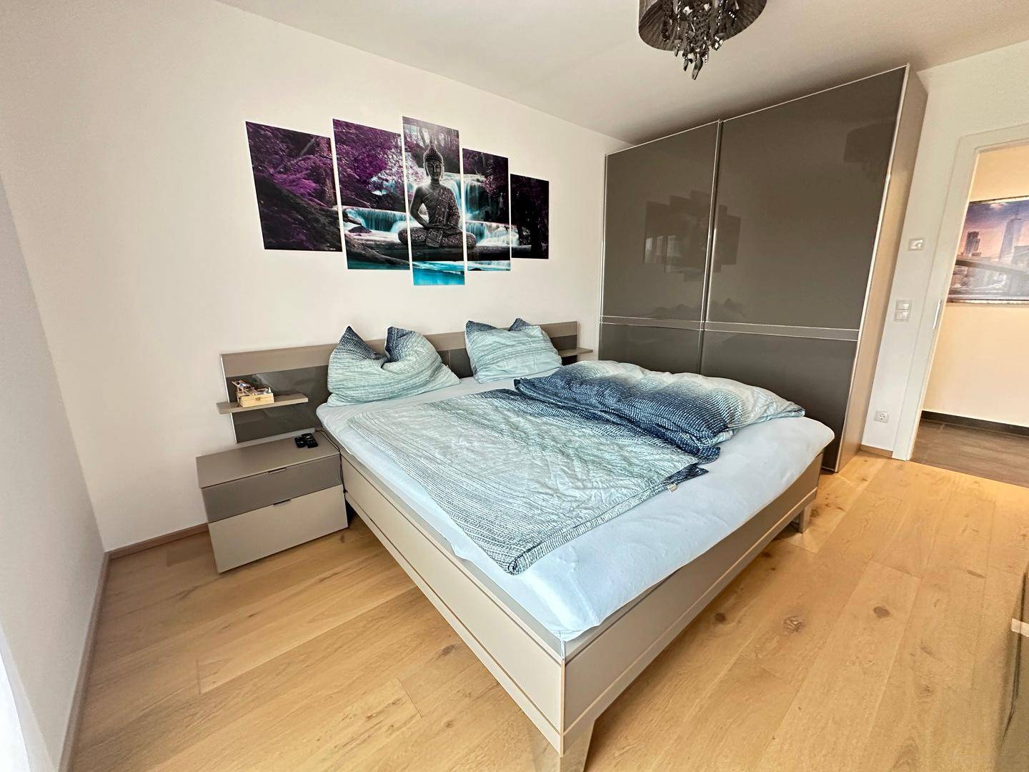 Modernes Schlafzimmer mit Holzboden, großem Kleiderschrank und stilvoller Dekoration.