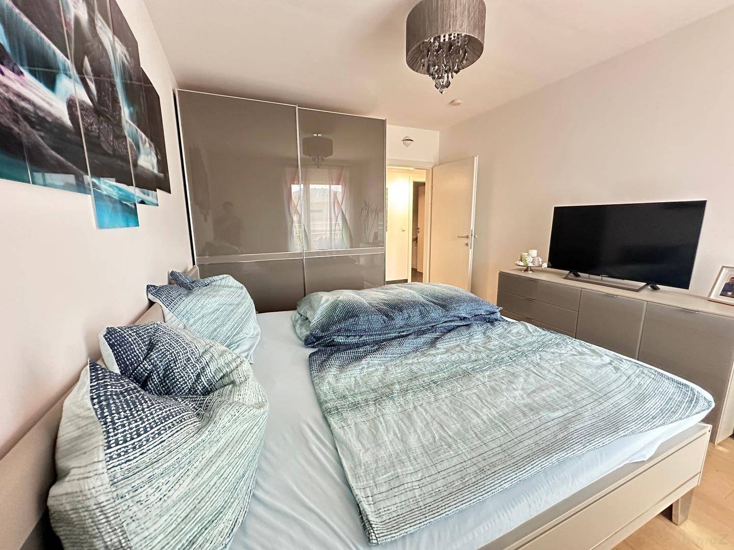 Gemütliches Schlafzimmer mit Holzboden, bequemen Bett und moderner Einrichtung.