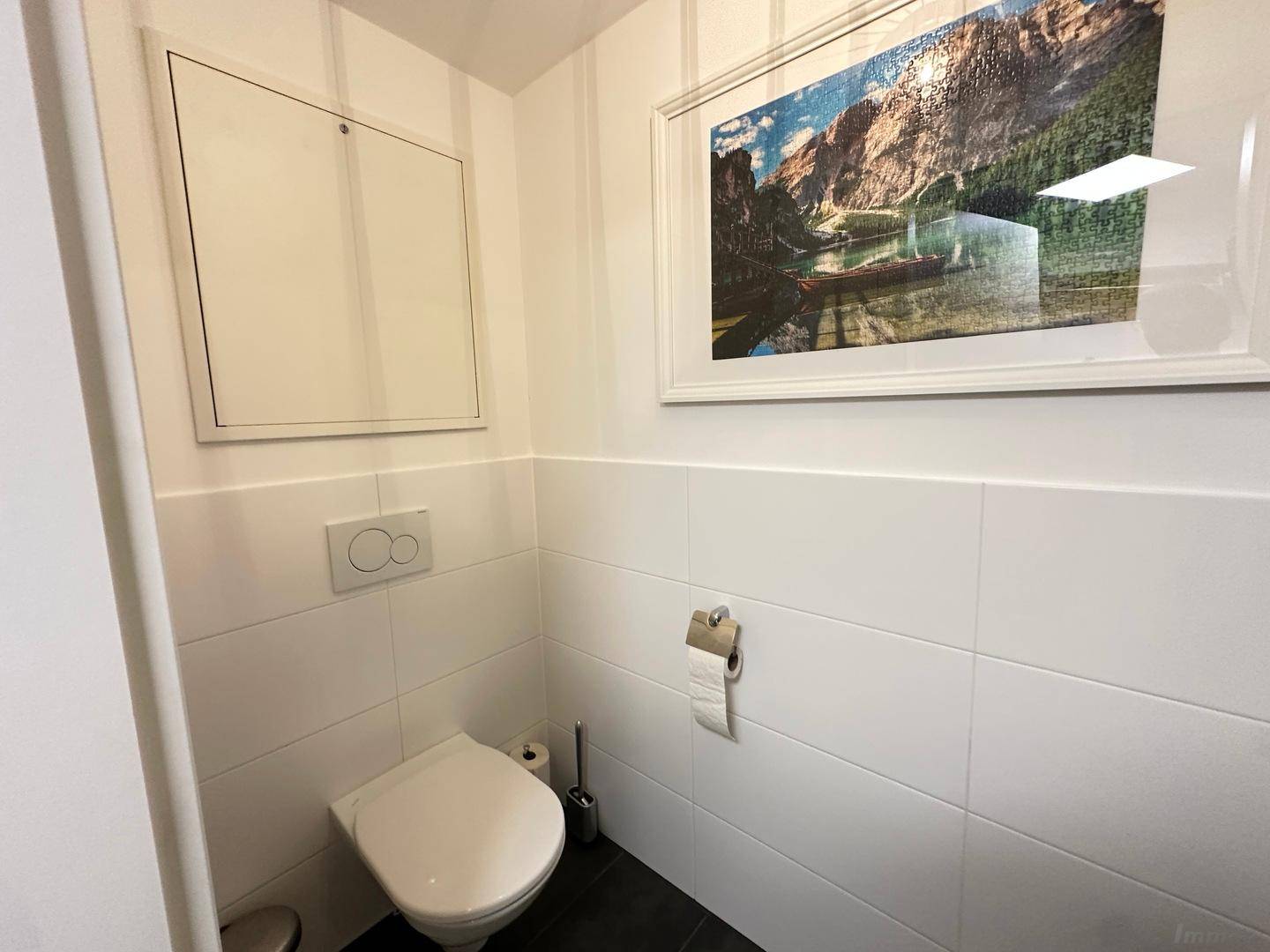 Sauberes Gäste-WC mit wandhängender Toilette und weiß gefliesten Wänden.