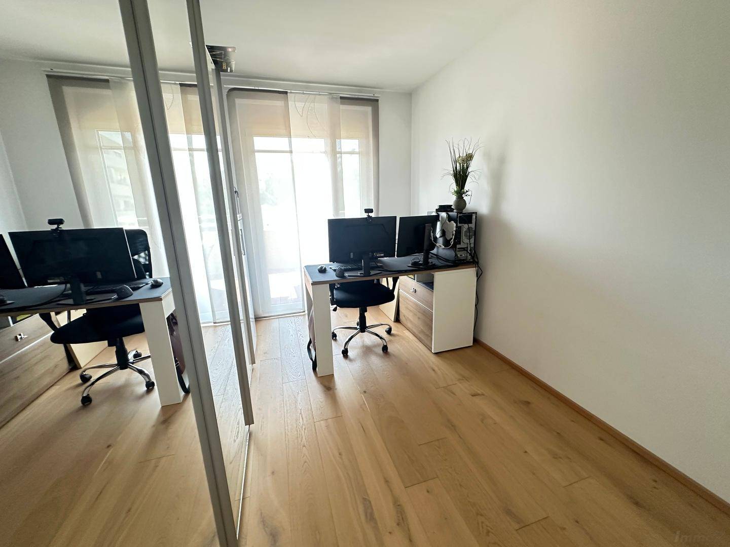 Modernes Arbeitszimmer mit Holzboden und großen Fenstern, ideal für Home-Office.