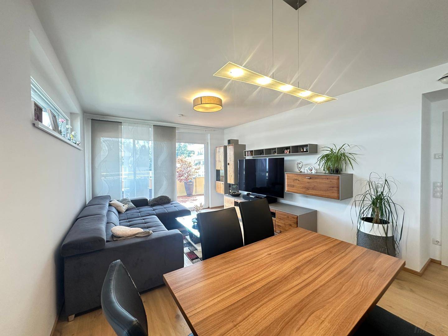 Heller Wohn-Essbereich mit Holzboden, Esstisch und Sofa, ideal für geselliges Beisammensein.