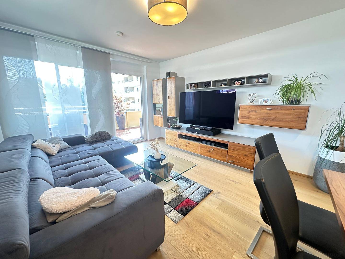 Gemütlicher Wohnbereich mit großem Sofa, TV-Möbeln und hellem Holzboden.