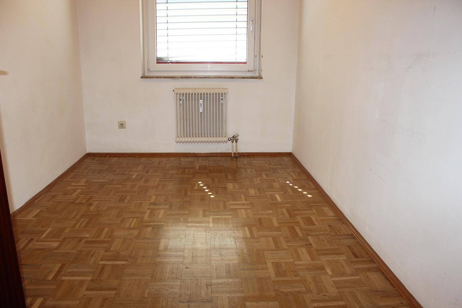 Geräumiges Schlafzimmer mit Parkettboden und einem Fenster, das für gute Belüftung sorgt.