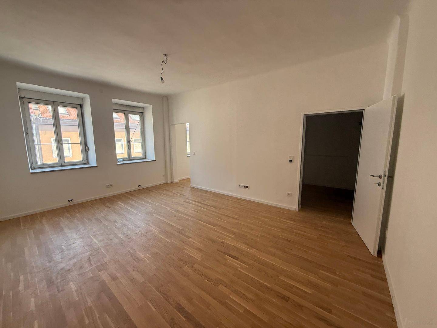 Geräumiges Zimmer mit hellem Parkettboden und zwei Fenstern, bietet vielseitige Nutzungsmöglichkeiten.