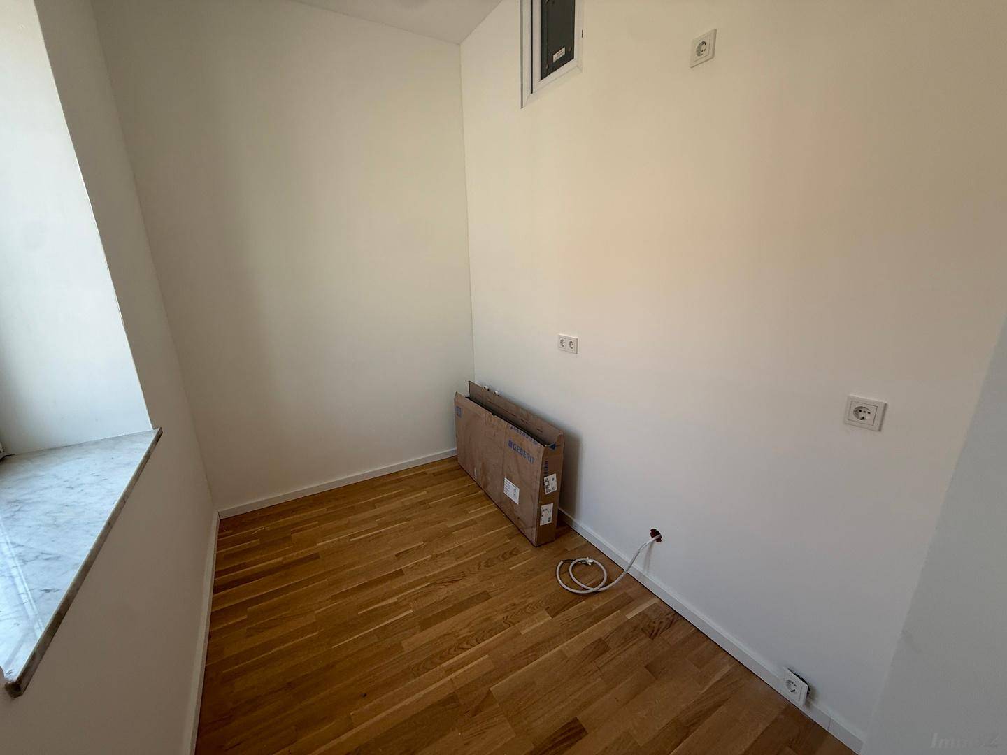 Kleiner Raum mit Parkettboden und Fenster, ideal als Abstellraum oder kleines Arbeitszimmer nutzbar.