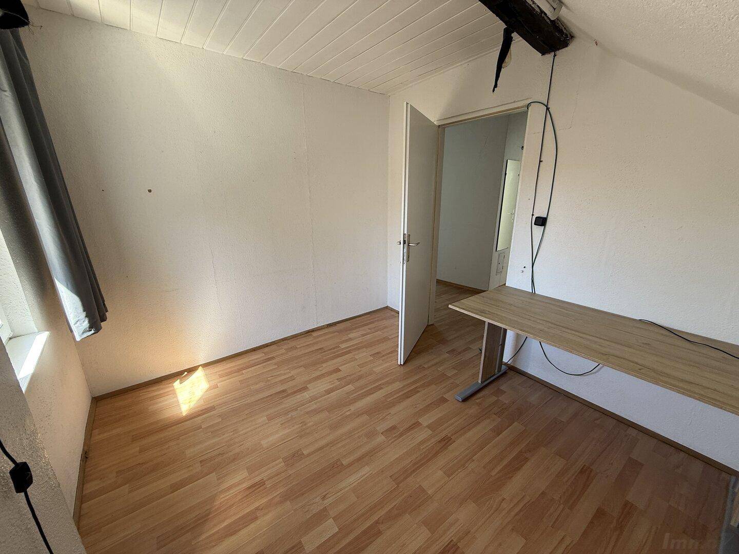 Geräumiges Dachzimmer mit Laminatboden und Fenster, bereit zur individuellen Gestaltung.