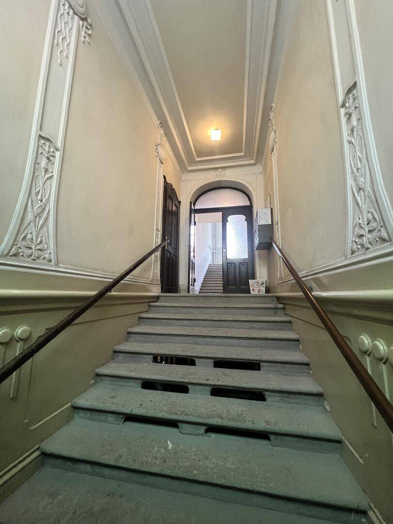 Historisches Treppenhaus mit kunstvollen Stuckverzierungen an Wänden und Decke, typisch für Altbauten.