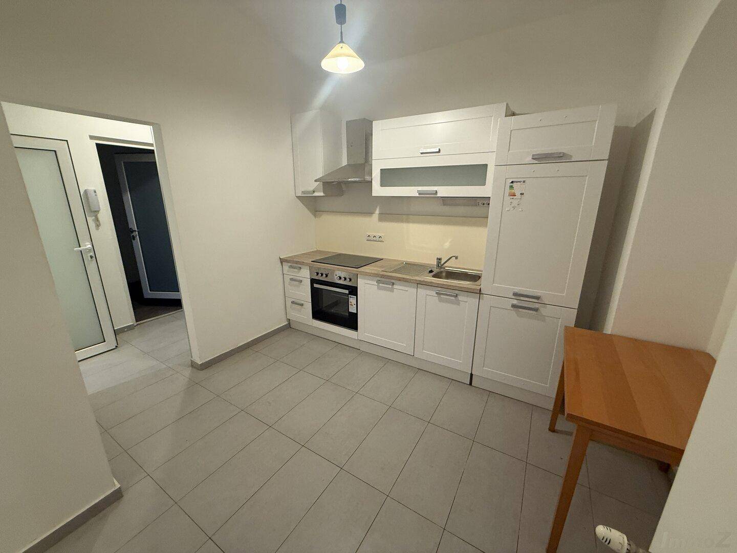 Funktionale Einbauküche mit weißen Schränken, Kochfeld, Backofen und Kühlschrank, ideal für kleine Haushalte.