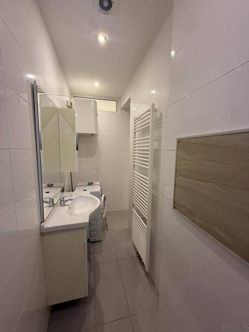 Funktionales Badezimmer mit Waschbecken, Spiegelschrank, Waschmaschine und beheiztem Handtuchhalter.