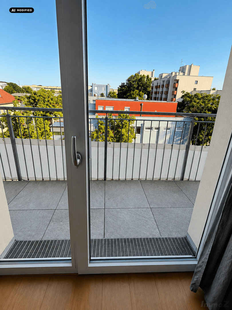 Geräumiger Balkon mit Fliesenboden und Blick auf die umliegenden Gebäude und Bäume.