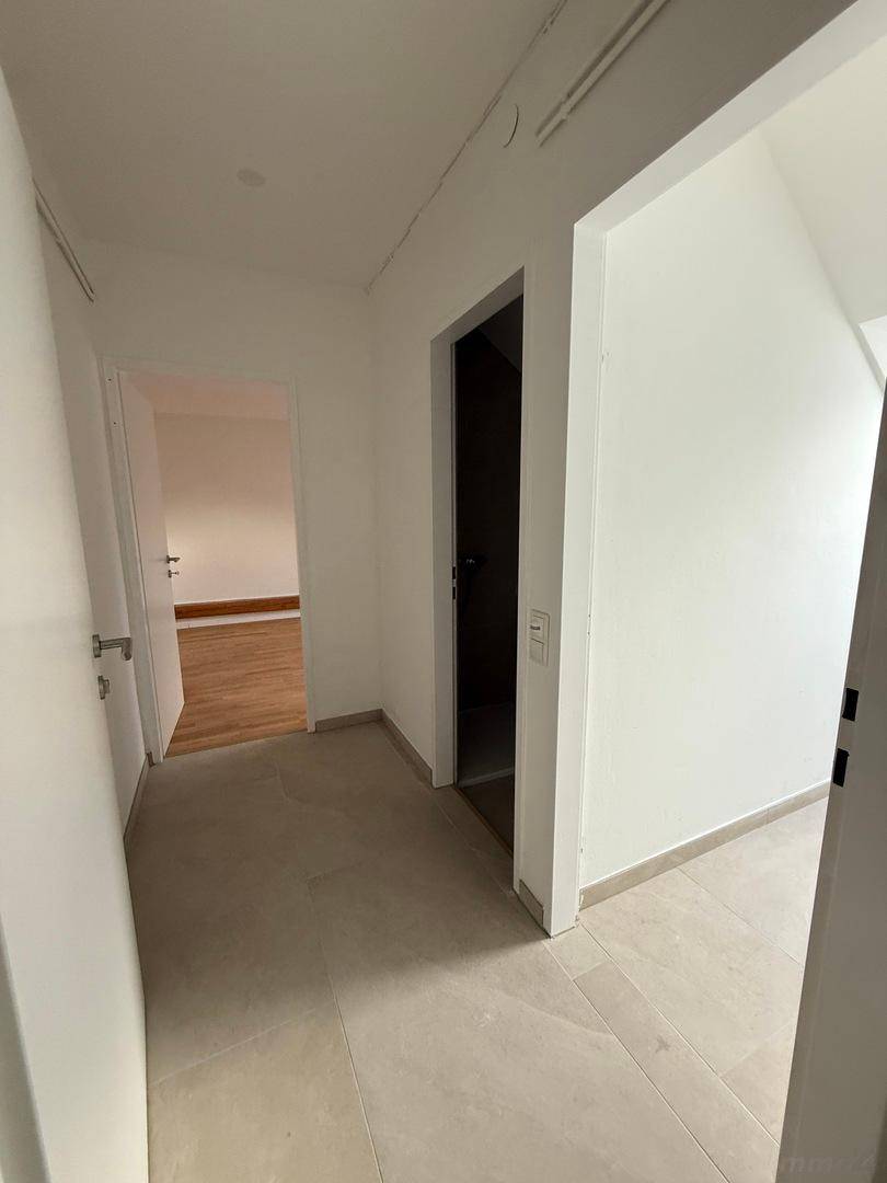 Heller Flur mit modernen Fliesen und Zugang zu verschiedenen Räumen in einem Neubau.