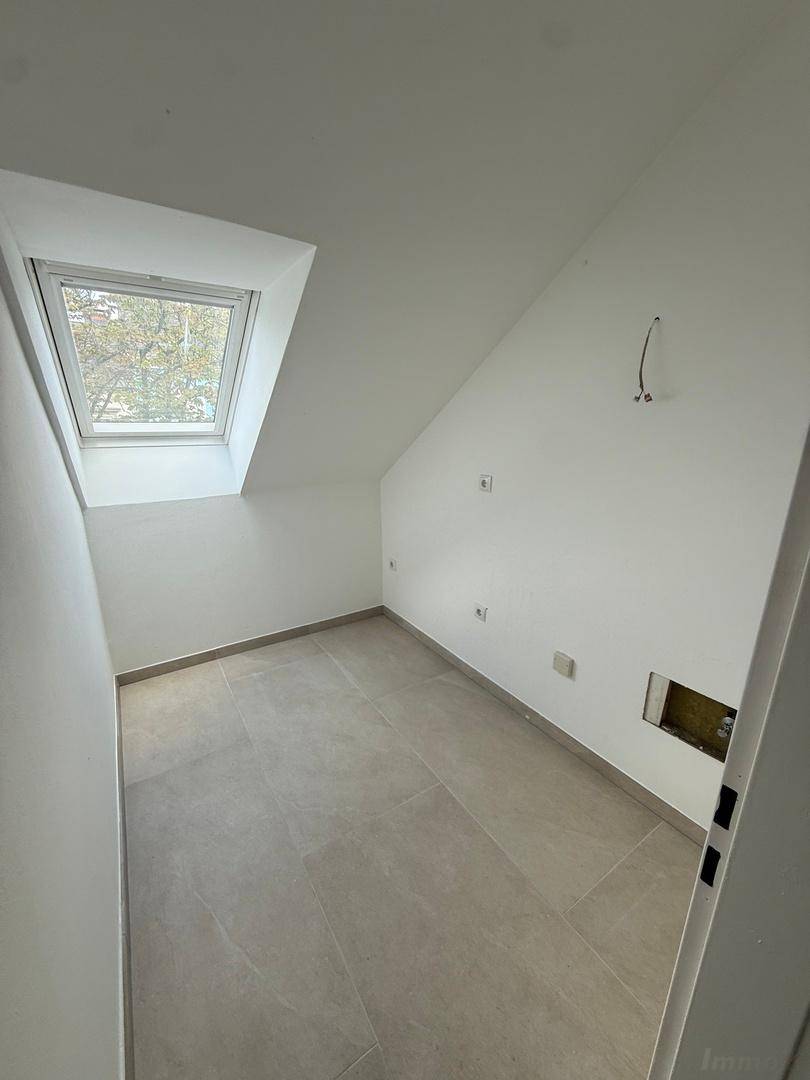Kleiner Raum im Dachgeschoss mit Dachfenster und Fliesenboden, vorbereitet für Installationen.