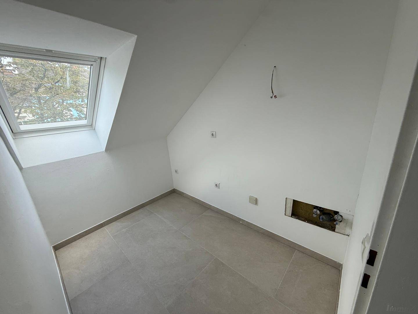 Dachgeschossraum mit schrägen Wänden, Dachfenster und Fliesenboden, ideal für individuelle Nutzung.