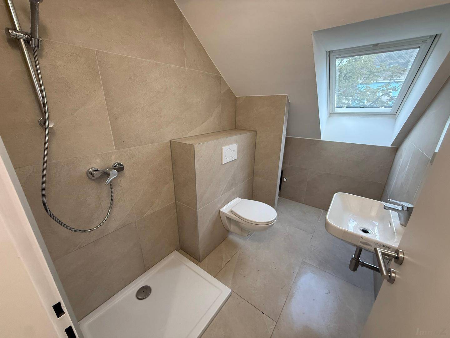 Modernes Badezimmer mit Dusche, WC, Waschbecken und Dachfenster.