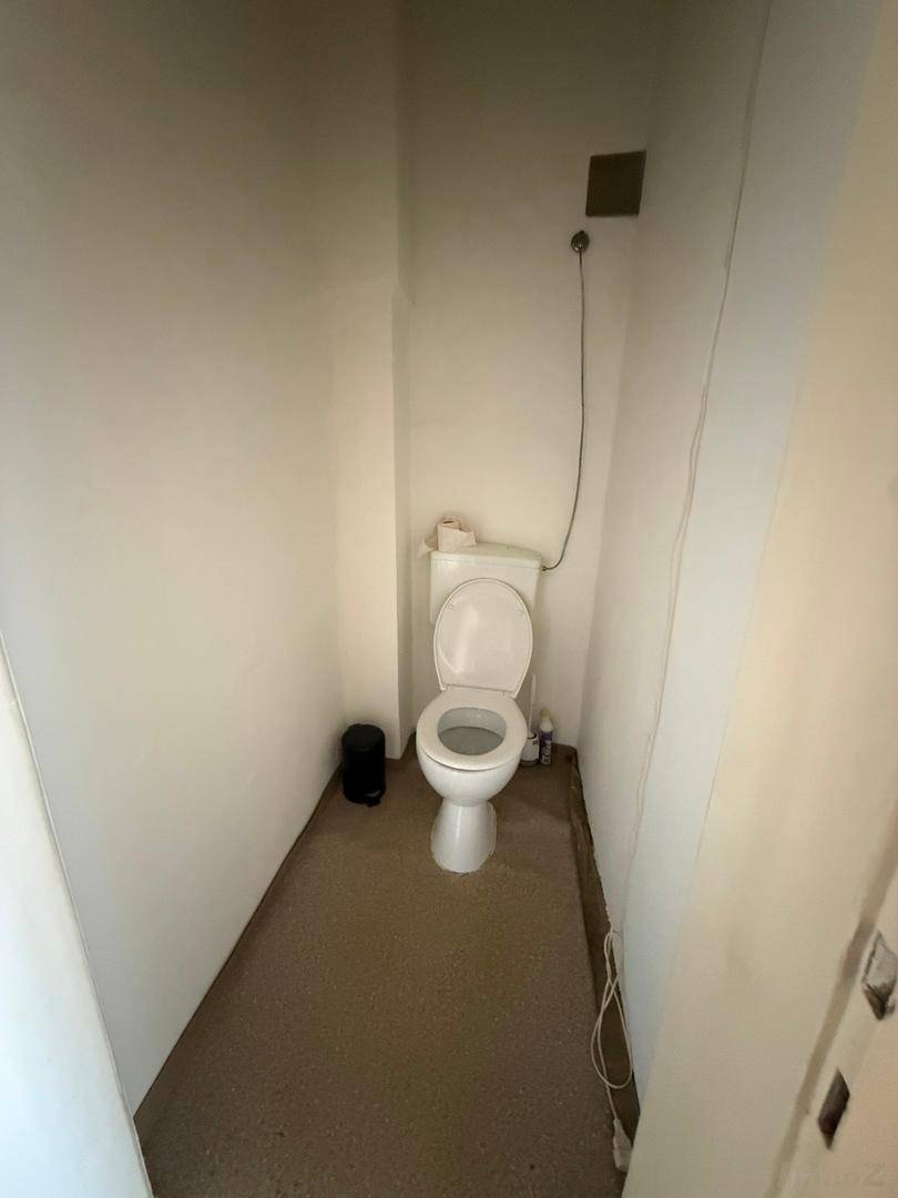 Kleines Gäste-WC mit einfacher Toilette, weißen Wänden und einem Lüftungsschlitz an der Decke.