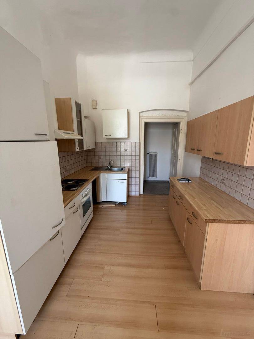 Voll ausgestattete Küche mit hellen Holzschränken, einfachen Geräten und Holzboden.