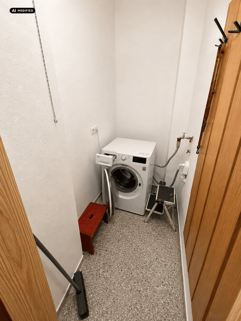 Kleiner Hauswirtschaftsraum mit Waschmaschine und pflegeleichtem Terrazzoboden.
