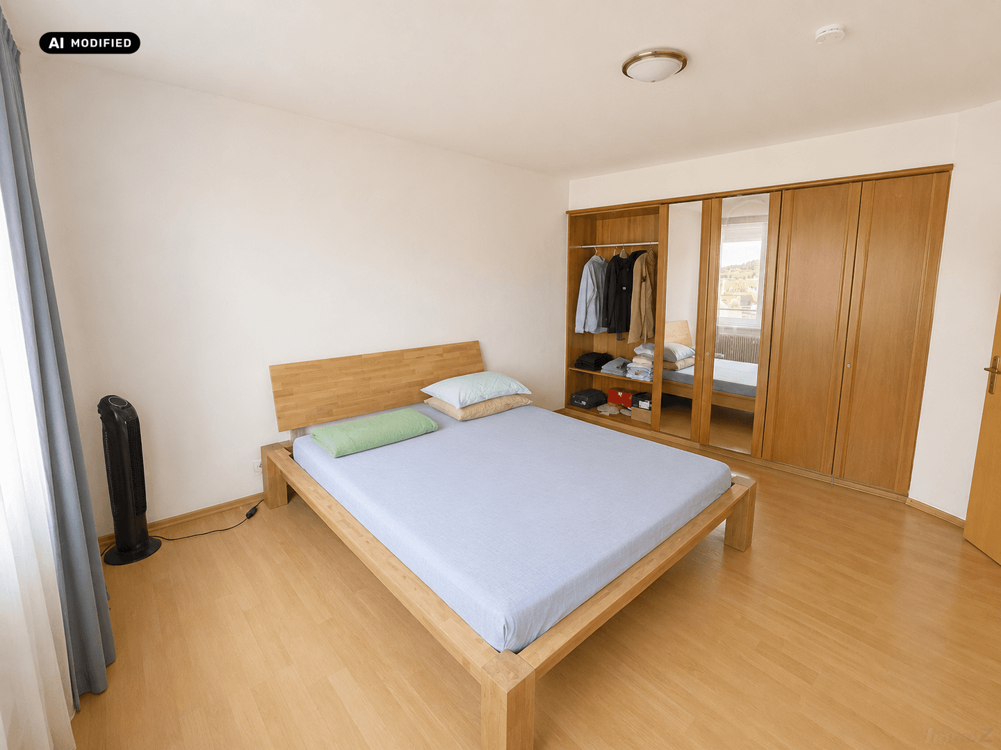 Geräumiges Schlafzimmer mit Holzbett und großem Kleiderschrank mit Spiegeltüren.