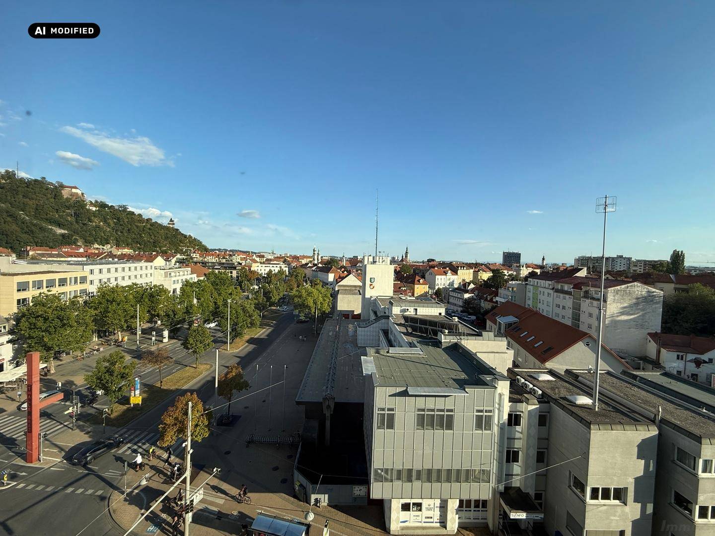 Weitläufiger Blick über die städtische Bebauung mit Straßen, Gebäuden und blauem Himmel.