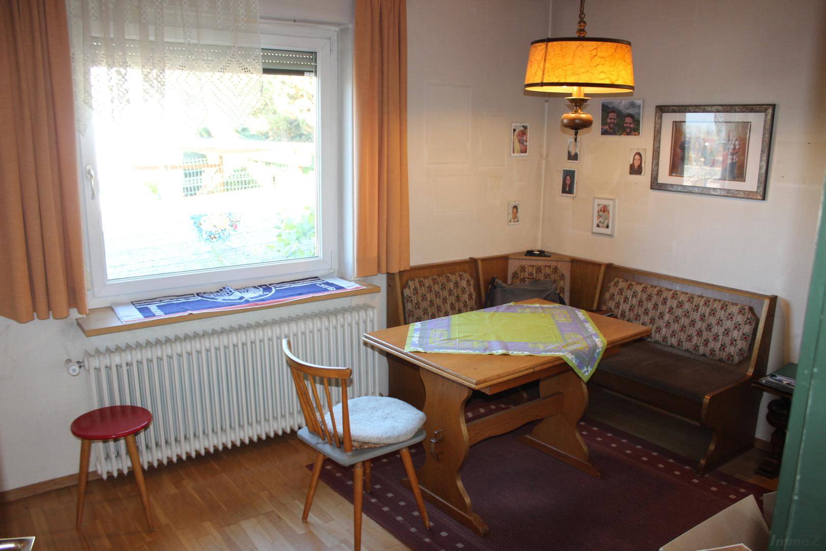 Gemütlicher Essbereich mit Eckbank, Holztisch und einem Fenster, das Tageslicht spendet.